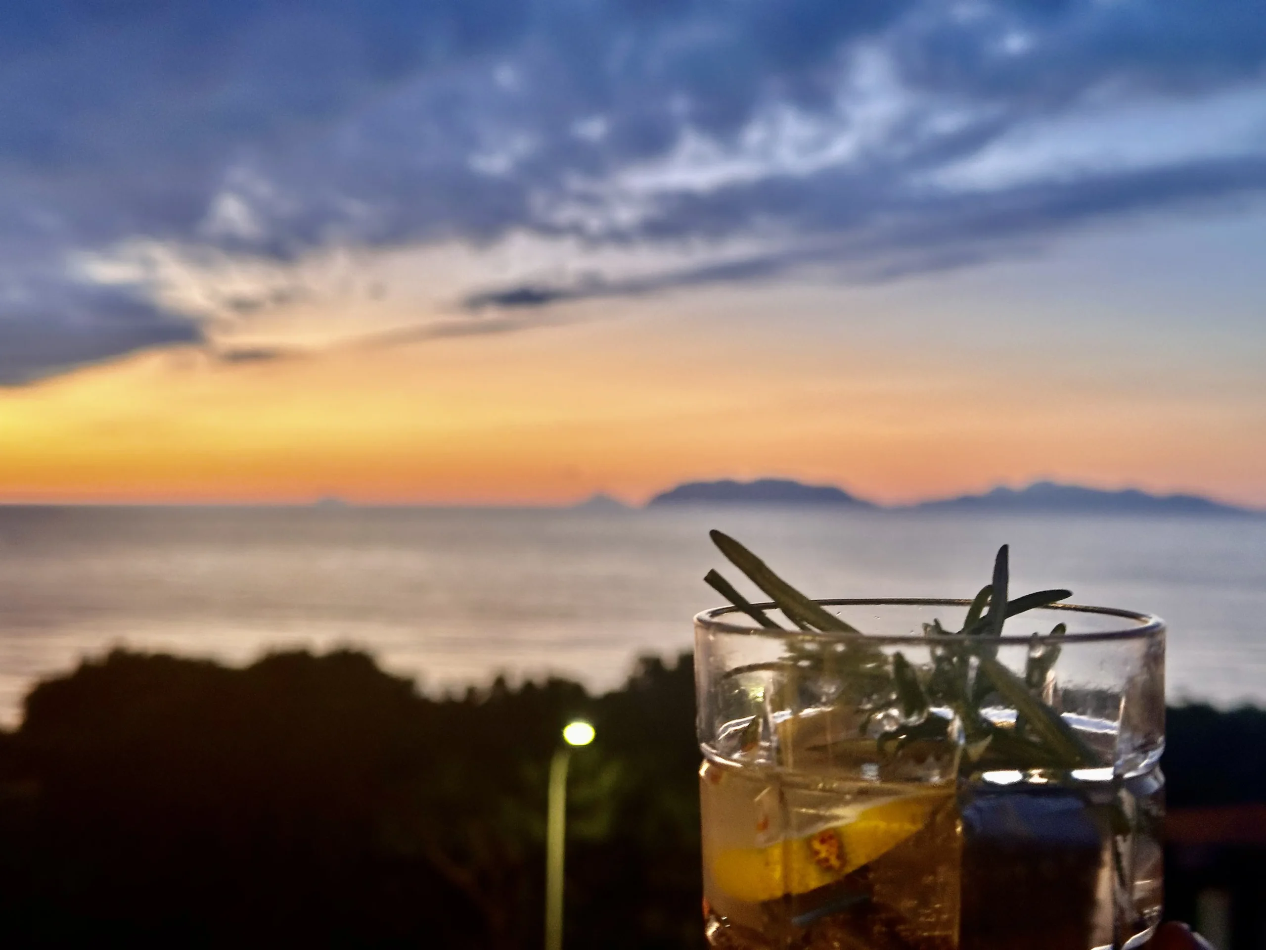 Taccuino aperto su un tavolino con vista sul mare a Milazzo, simbolo di un diario di viaggio
